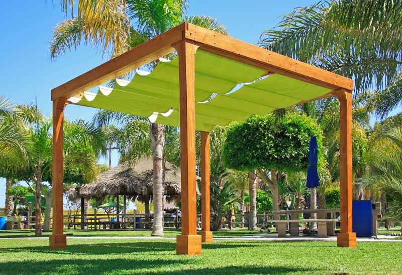A redwood pergola with a green retractable canopy